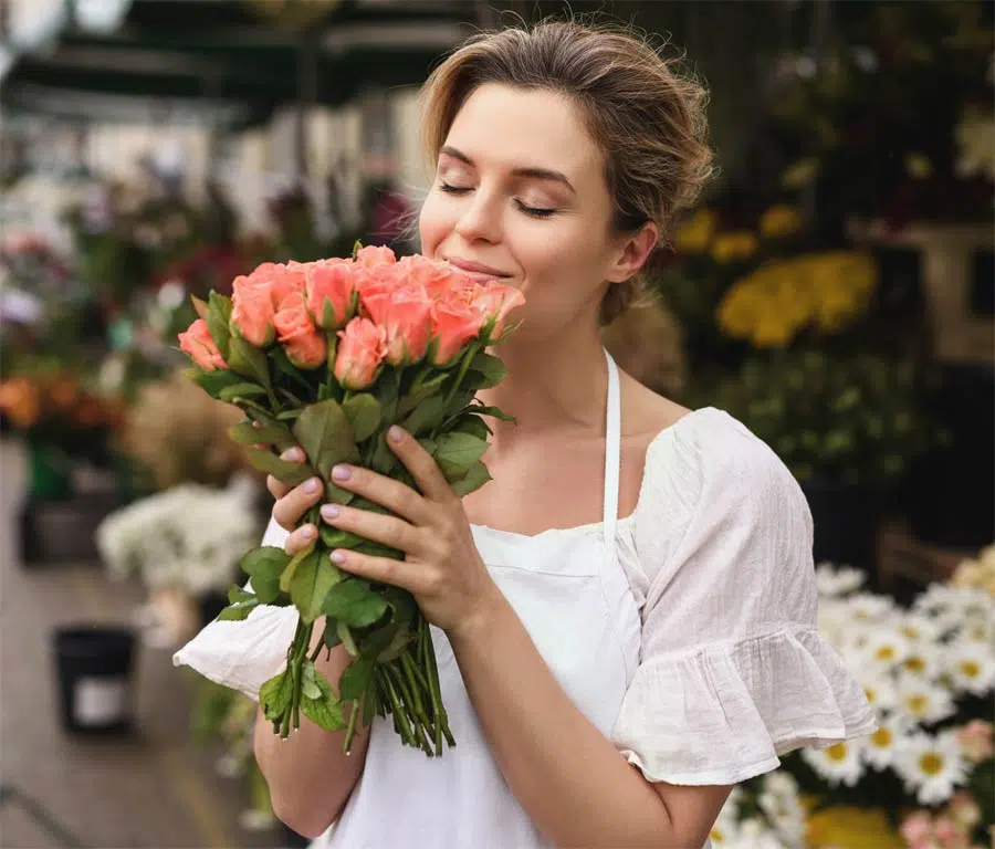 Femme sent un bouquet de fleurs.